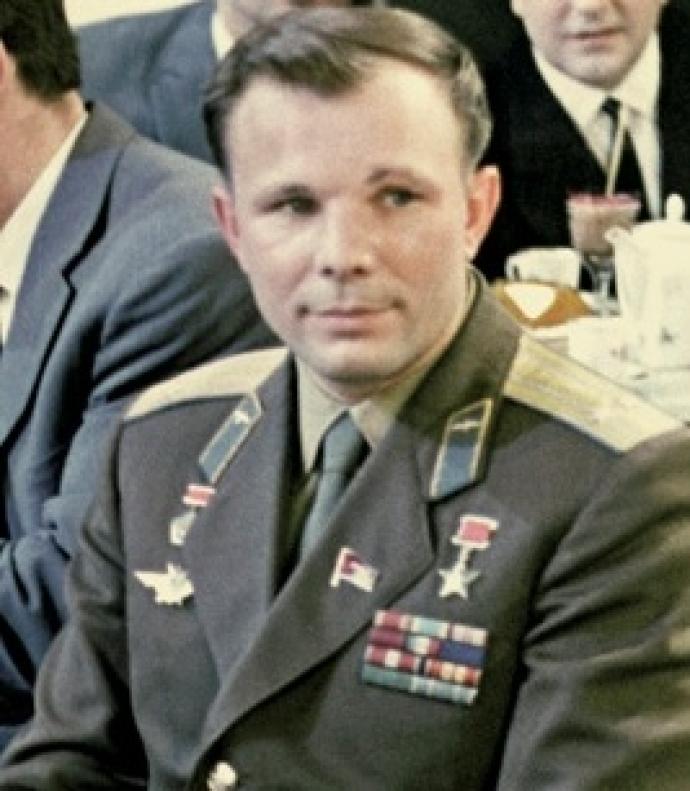 A photograph of Yuri Gagarin, the first human to travel into space, wearing a military uniform with various medals and insignia. He is seated with a composed expression, symbolizing his historic achievement as a Soviet cosmonaut