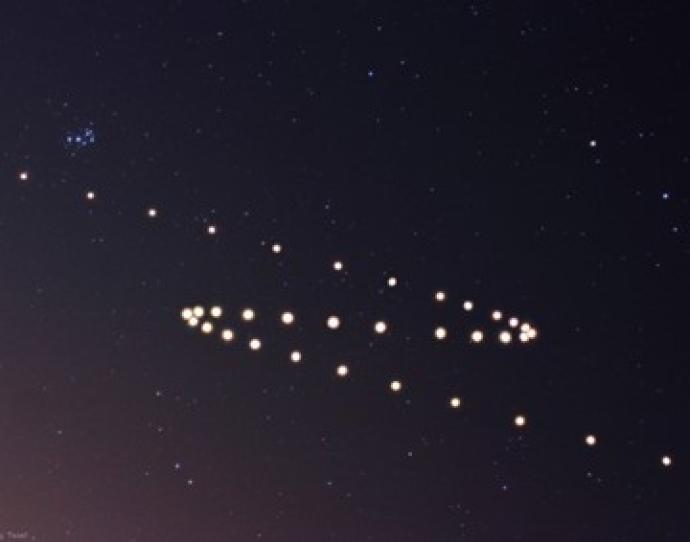 Time-lapse image of Mars in retrograde motion, showing a looped path of bright dots in the night sky against a background of stars